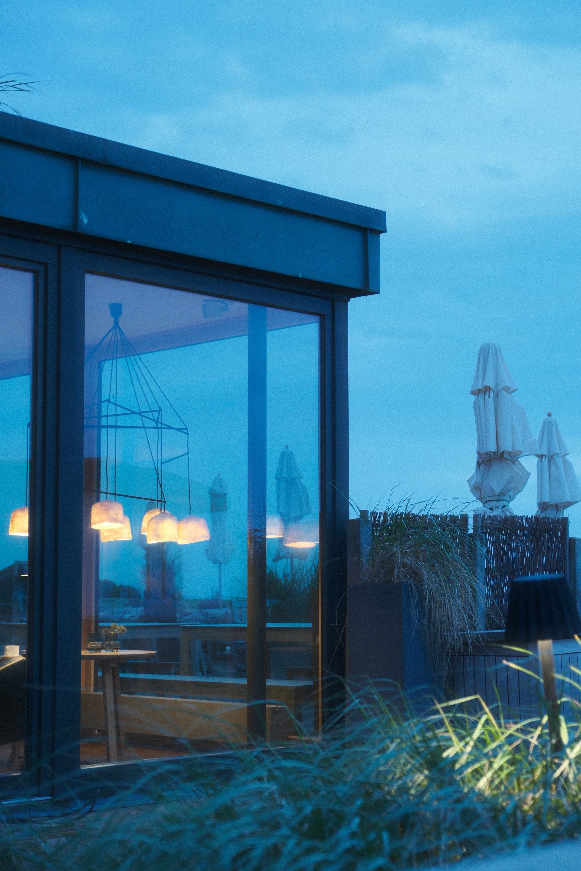 Ein beleuchtetes Zimmer mit großen Fenstern in der blauen Stunde.